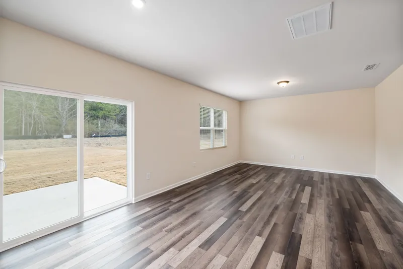 An empty finished room shows varied wood-look flooring, white baseboards, and a sliding glass patio door.