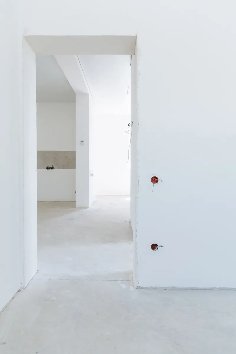 White interior walls and untrimmed door openings surround exposed electrical boxes before final fixtures.