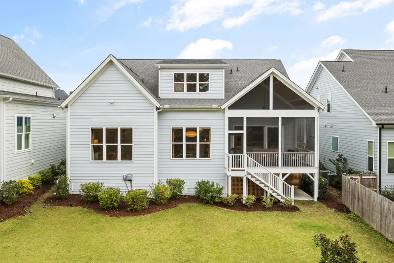 A finished house rear elevation combines horizontal lap siding, a shingled roof, and a raised screened porch with stairs.