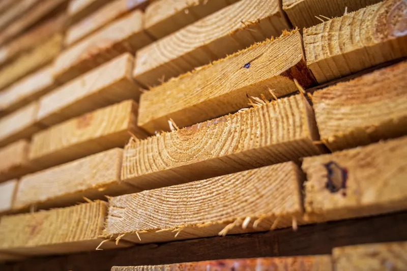 Stacked rough-sawn lumber shows board ends and wood grain ready for construction supply.