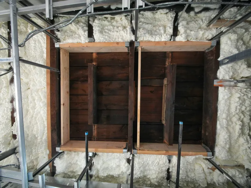 Spray foam fills wall cavities around wood blocking and metal framing before the wall is closed.