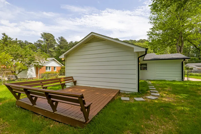 A low wood deck with built-in benches meets a finished lap-sided house and its backyard.